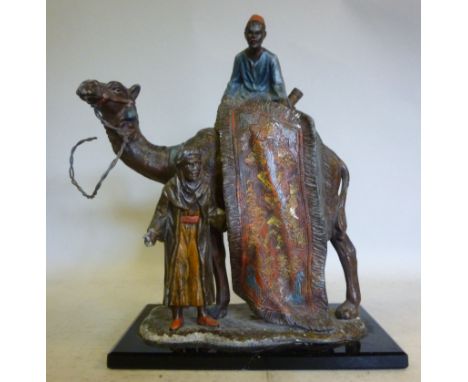 An early 20thC painted spelter novelty table lighter, fashioned as an Egyptian camel and two Arab carpet sellers, on a cerami