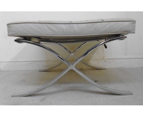 A 1960s Barcelona stool, having a buttoned beige hide upholstered, box cushion seat, buckled to the strapped, crossover stain