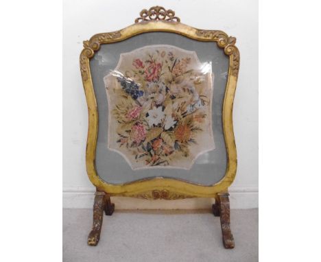 A mid 19thC carved giltwood framed firescreen with foliate scrolled ornament, set with a tapestry panel, featuring a bouquet 