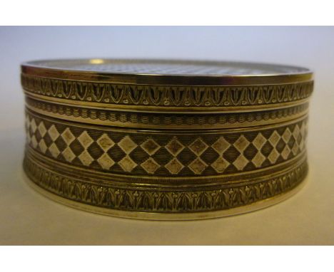A French silver coloured metal circular pin box and cover with cast and engine turned decoration and a gilded interior