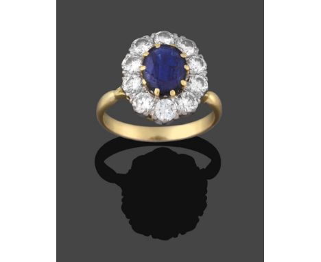A Sapphire and Diamond Cluster Ring, the oval cut sapphire in a yellow claw setting, within a border of round brilliant cut d