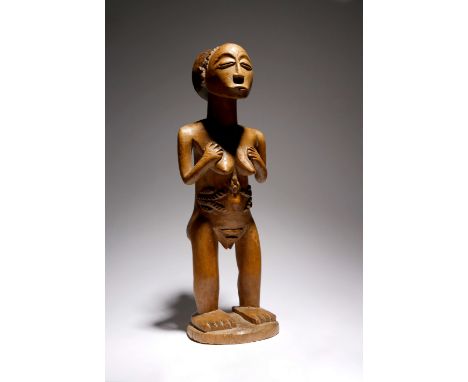 A Luba Hemba standing female figure Democratic Republic of Congo with a disc and conical coiffure with carved chevrons, the s