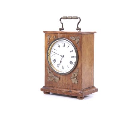 An early 20th century oak cased mantel clock. White dial with Roman numerals brass bezel, applied acorn and oak leaf spandrel