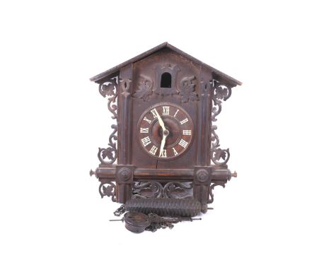 A vintage cuckoo clock and a selection of clock spares. The cuckoo clock having a wooden frame with pierced decoration, the d