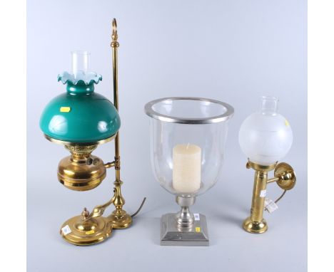 A brass oil lamp style table lamp, another similar, and a candle stand with storm shade