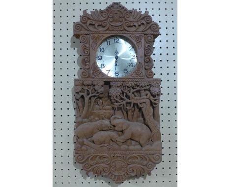 A Southeast Asian clock, the elaborately carved case with elephants and scrolling foliage, quartz movement, the round dial wi