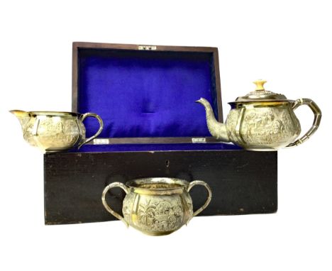 INDIAN WHITE METAL THREE PIECE TEA SERVICE, comprising tea pot, sugar and cream, each embossed with panels of figures, animal