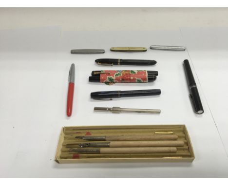 A box containing a collection of fountain pens, pen knives and a cased thermometer with inspection certificate