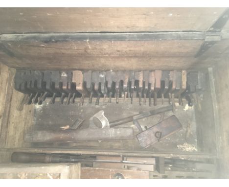 A carpenters chest containing a large collection of woodworking planes and carpentry tools