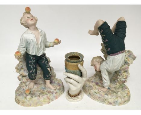 A pair of bisque ceramic figures in the form of a boy juggling apples and a Worcester vase in the form of a hand (3)