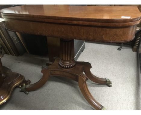 A regency mahogany card table the twin flap top above a fluted pillar on splayed legs