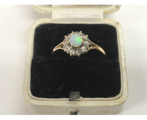 An 18ct gold ring set with a central opal surrounded by diamonds, approx 2.9g and size P.