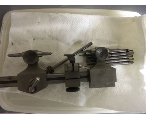 A box containing a collection of watch makers tools including two watch makers lathes, milling bits, clock faces etc