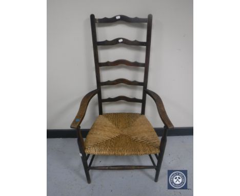 An antique ladder back rush-seated armchair
