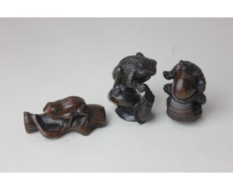 Two Japanese wood netsuke of toads, to include one standing on a snail, 5.5cm high, both with character marks, together with 