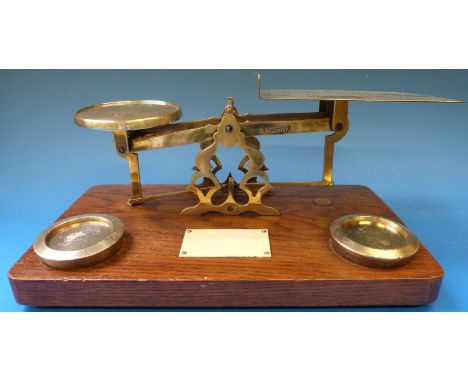 A set of brass parcel scales with ivorine plaque and 1lb weights to the oak base, possibly Samuel Senior 
