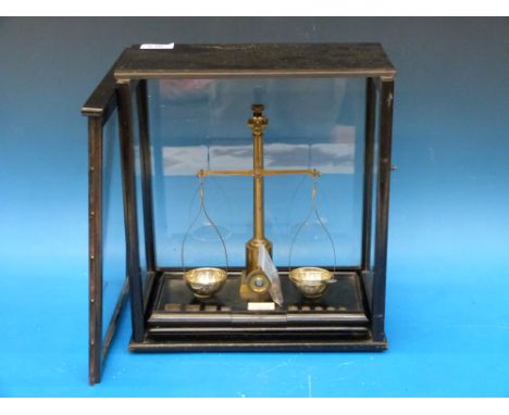 A glass cased set of diamond beam scales with weights 