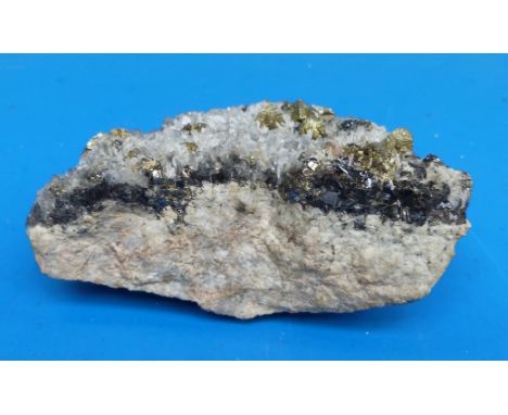 A small geological sample formed of light and dark grey crystals on a rock bed, approximately 9cm long 