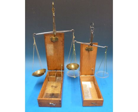 A cased set of travelling beam scales, the case lid, when held open  supporting the steel beam with two brass bowls with a qu