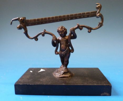 A set of 18thC bronze scales, formed as a cherub supporting scrolling mounts, on a black marble base 