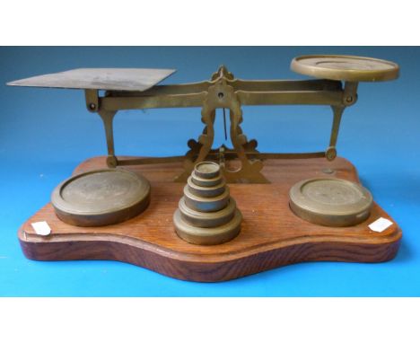 A set of brass postage scales on a oak base with a run of weights ½ oz to 3lb