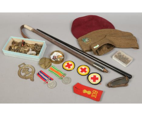 A collection of militaria including World Ward II and defence medals an ebonized swagger stick, berets, buttons and badges et