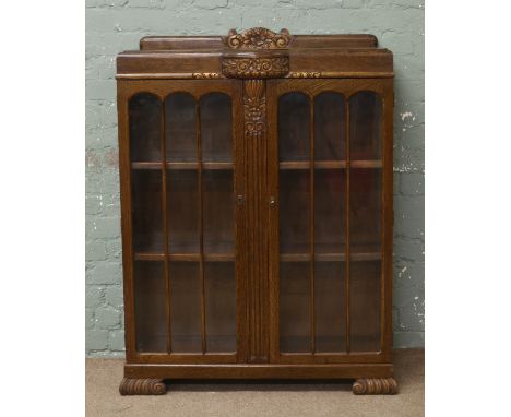 A carved oak display cabinet raised on carved bracket feet.