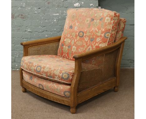 A Ercol light oak arm chair with floral decorated cushions.