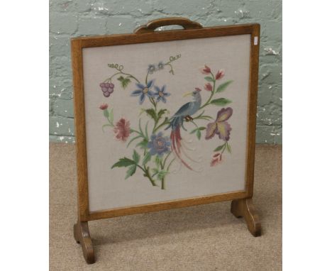 An oak firescreen with woolwork parcel depicting a bird and flowers.