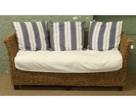 A rope effect conservatory sofa with blue and white striped cushions.