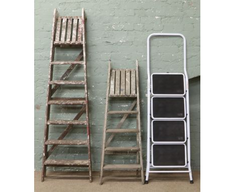 Two sets of vintage wooden step ladders, along with a set of metal steps.