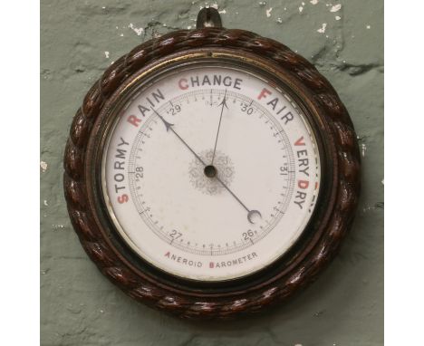 An early 20th century oak aneroid wall barometer carved with rope twist moulding.