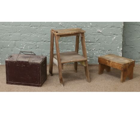 A rustic set of wooden steps, along with a wooden foot rest and a vintage ammunition box.