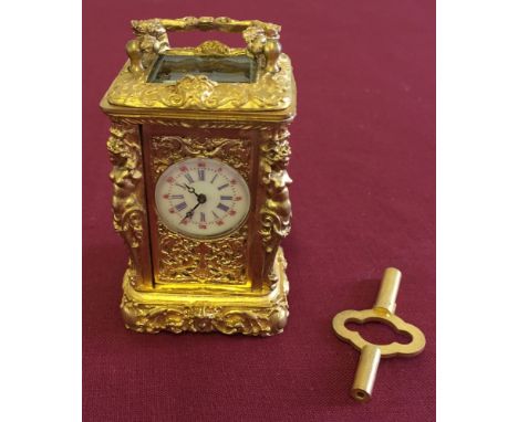 A Miniature gilt metal carriage clock with enamel dial in working order, 7cm tall.
