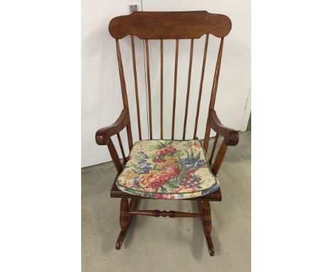 Modern oak stick back rocking chair with floral cushion.