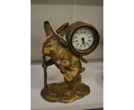A novelty brass mantel clock modelled as a rabbit carrying some firewood on his back.