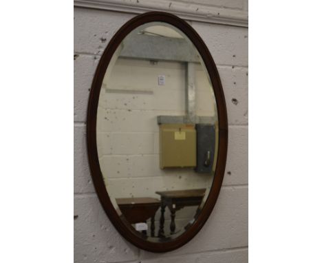 A mahogany framed oval wall mirror and a Victorian walnut over-mantel mirror.