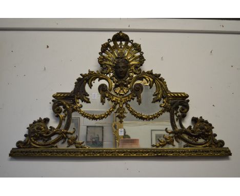 A highly ornate brass over-mantel mirror with female mask, swags, C scrolls etc.