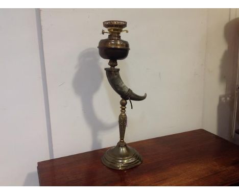 An early 20th century gilt-metal and cow horn oil lamp, the horn mounted on a leaf-cast gilt-metal baluster stem on a stepped