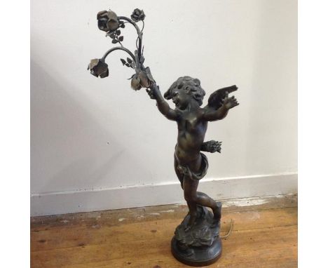 After Auguste Moreau, a late 19th century spelter figural lamp, modelled as Cupid, standing with arms aloft, one supporting a