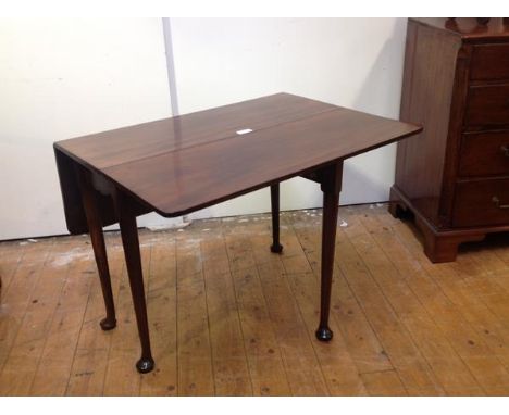 A George III mahogany gate leg supper table, the rectangular top with rounded corners above a scalloped apron, raised on tape
