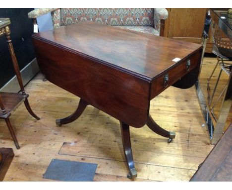 A Regency mahogany sofa table, of characteristic form, fitted with a frieze drawer opposed by a dummy, each with lion mask ha