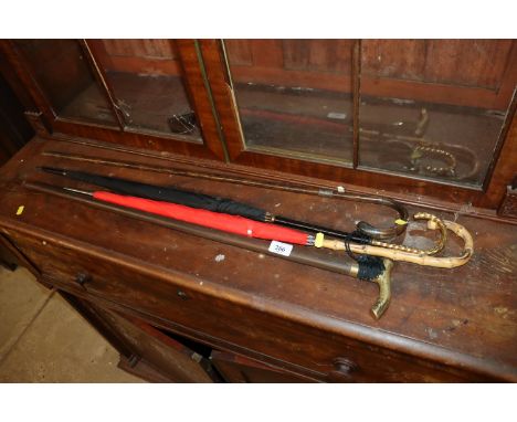 A vintage cane and white metal mounted walking stick; another modern walking stick and two umbrellas