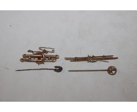 A 9ct gold brooch decorated with a bird; a yellow metal brooch; and two yellow metal mounted stick pins 