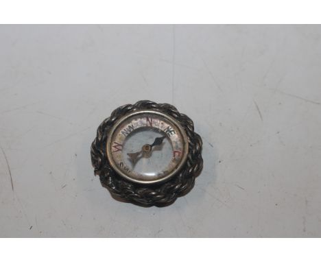 A miniature compass with white metal rope twist surround