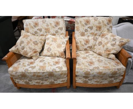 An Ercol ash and woven cane bergere three piece suite, two seater sofa and pair of armchairs, upholstered in Arts and Crafts 