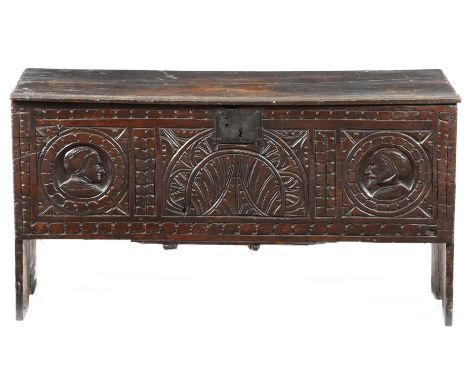 A 17th century oak coffer, the hinged lid with moulded and crimped edges, the front with a central leaf carved lunette flanke