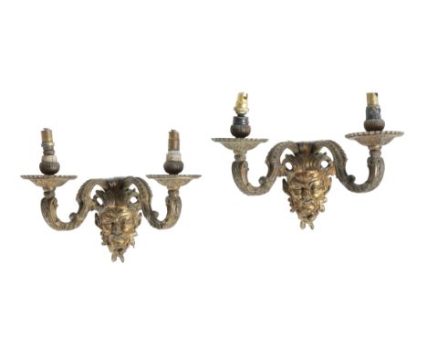 A set of four French ormolu twin-light wall appliques in Regence style, each with a winged male mask backplate issuing a pair