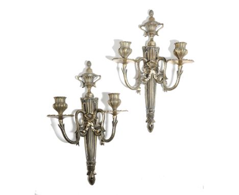 A pair of 18th century continental brass twin-light wall appliques, each with an urn surmount with a cone finial above a flut