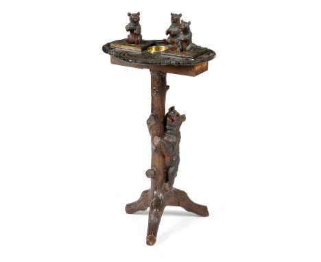 A Black Forest carved wood smoker's table, the naturalistic shaped and pierced top with three seated bears, with two hinged c